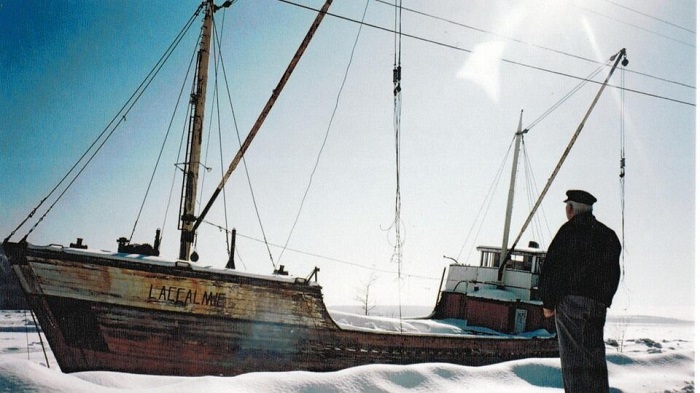 Éloi Perron devant son ancien navire, à Baie-Saint-Paul | Photo @ Famille Perron, avec courtoisie https://ici.radio-canada.ca/nouvelle/1086519/vestiges-goelette-accalmie-capitaine-baie-st-paul