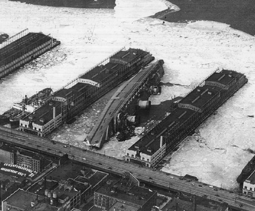 Le Normandie (USS Lafayette) couché sur son flanc gauche après l'incendie | Par USN — Dictionary of American Naval Fighting Ships (DANFS), National Archives Photograph, 80-G-410243, Domaine public, https://commons.wikimedia.org/w/index.php?curid=4254838